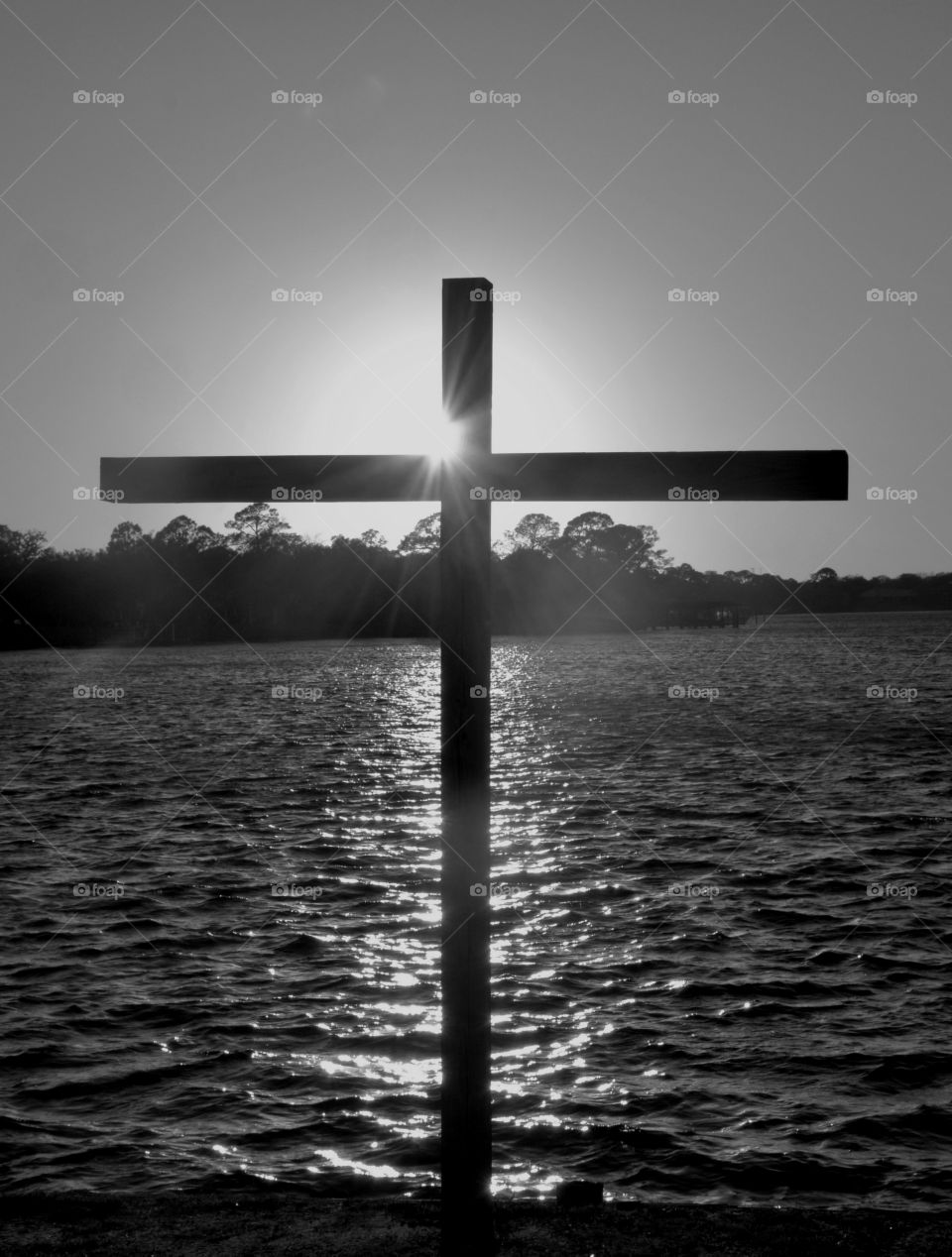 Glorious sunset!
A wooden cross stands erect at the waters edge deflecting the bright sun!