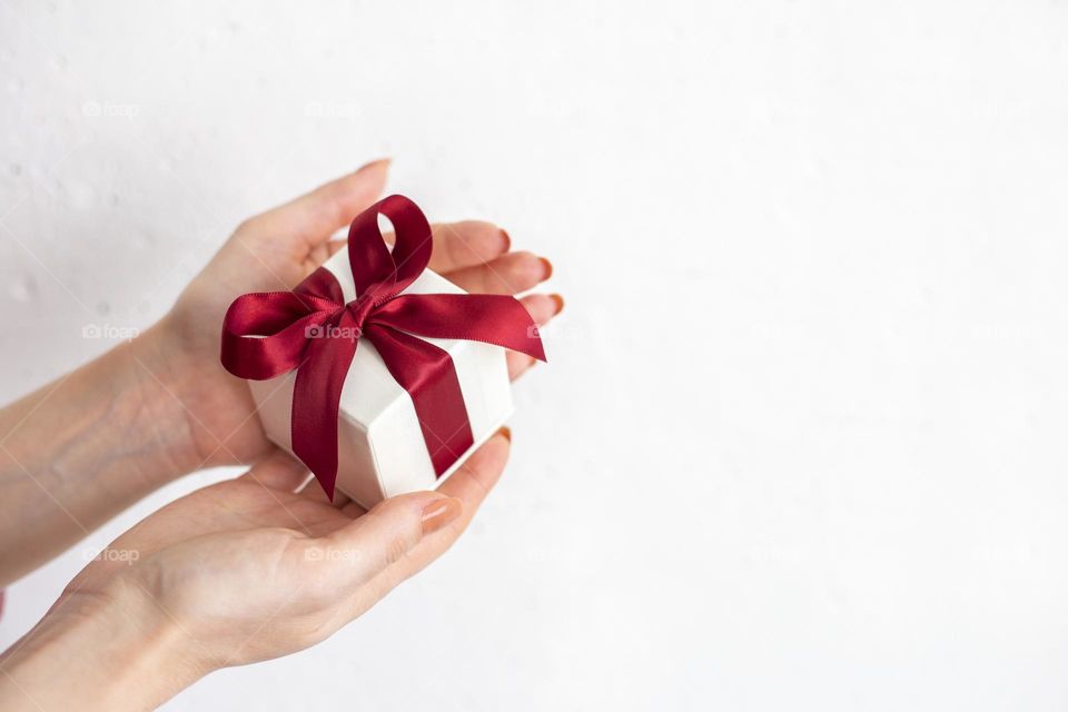 Female hands holding gift box with red bow