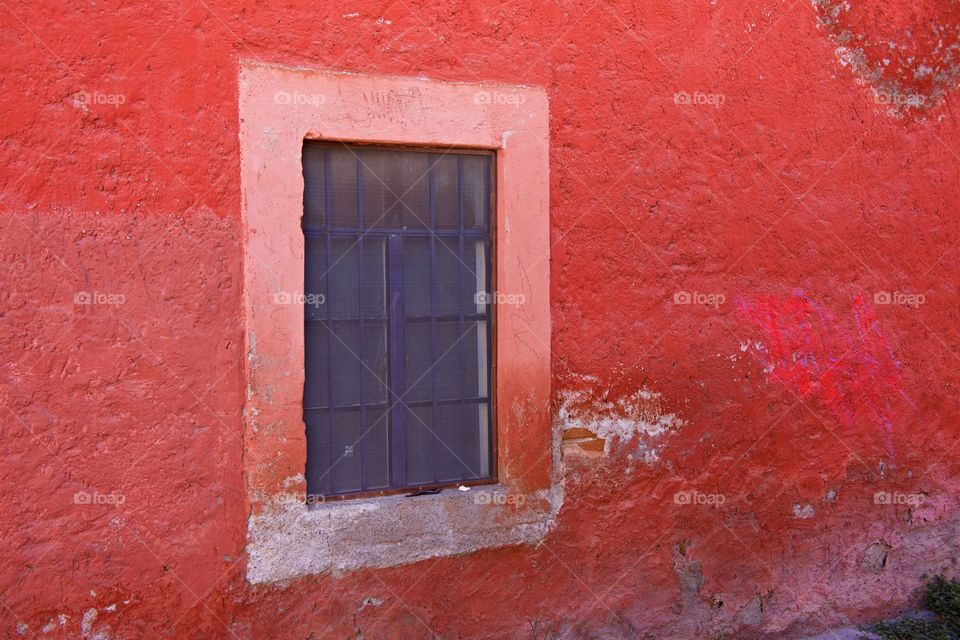 Rough red painted wall with window