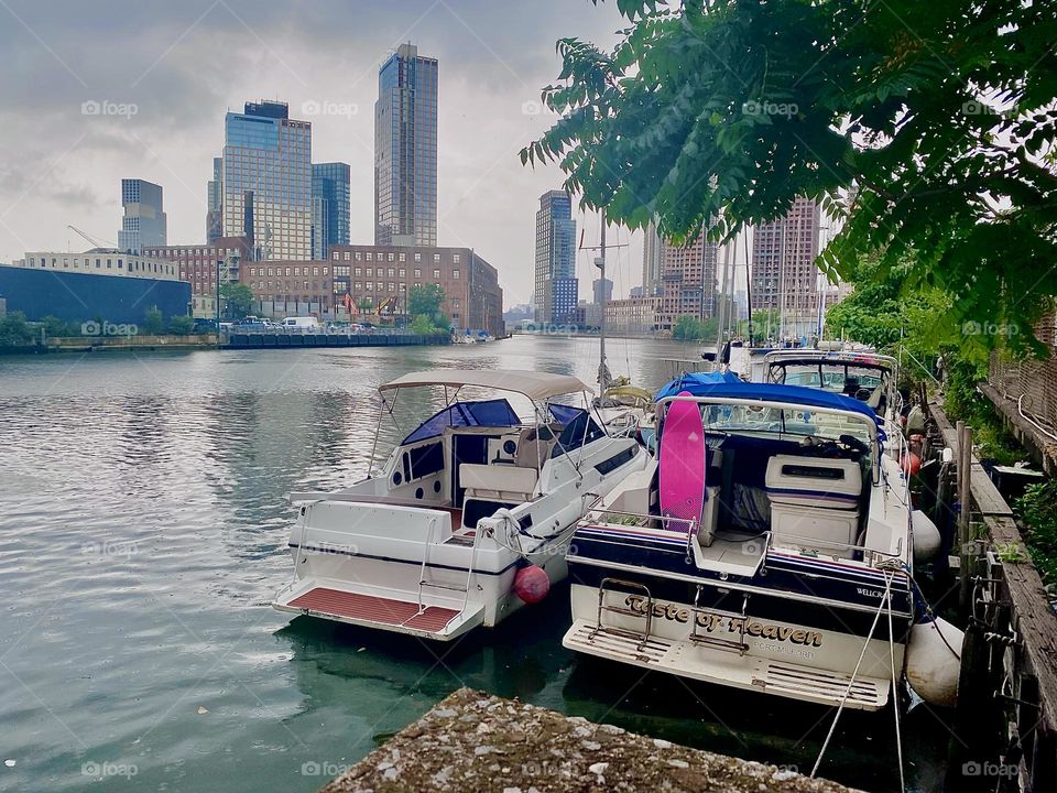 These beautiful boats are tied to the “Long Island City” shore by the “Pulaski Bridge” at “Newtown Creek”. The partially overcast day causes the water’s surface to appear with a silvery sheen like glass. 2023. Hypnotic Productions