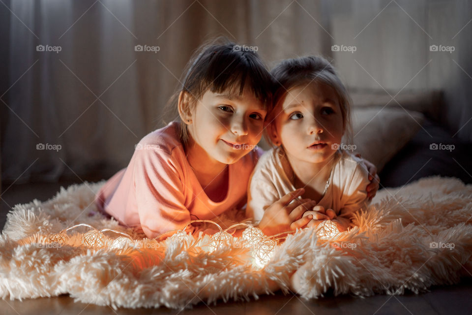 Little sisters reading a book at Christmas time 