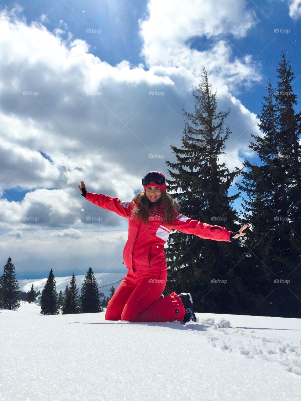 Happy woman dressed in winter clothes enjoying the snow on a bright sunny day