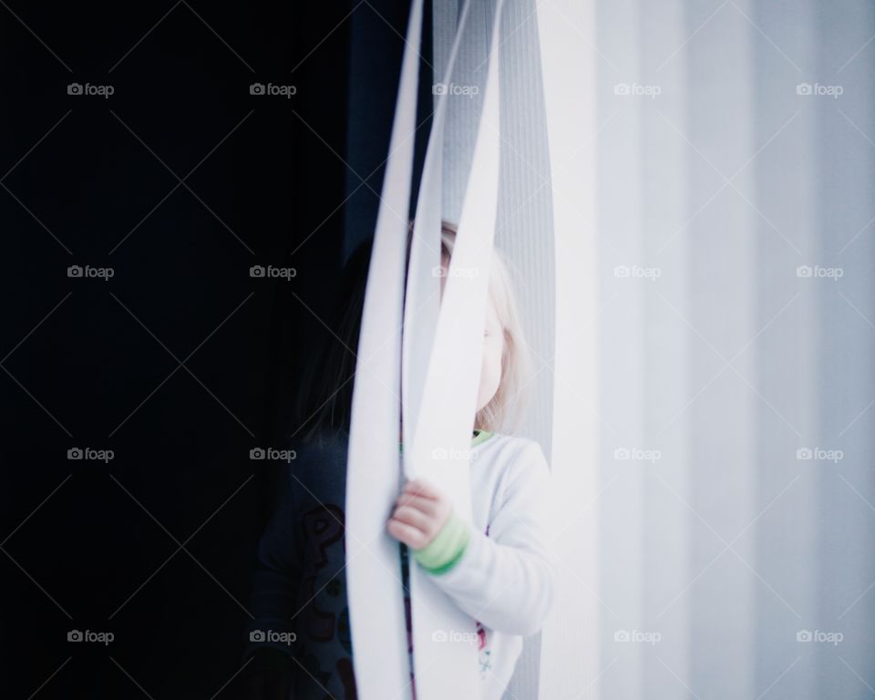 Little girl hiding in the curtains. 