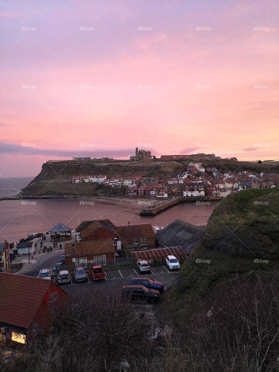 Sunset over Whitby Abbey with the sea and houses in foreground