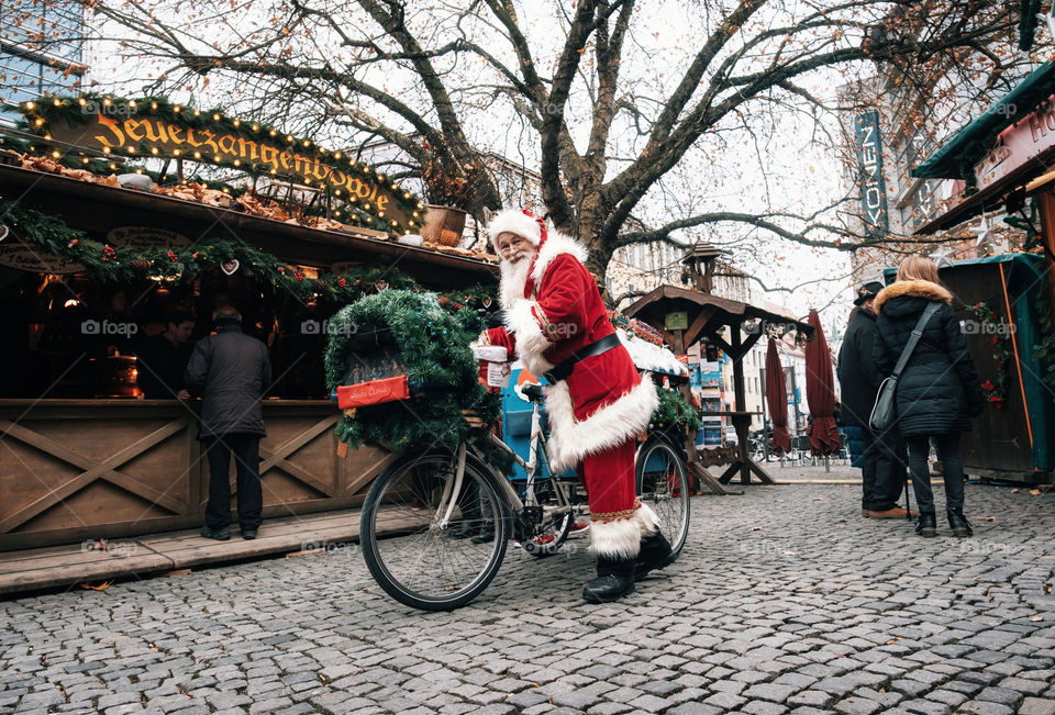Santa Claus with magic bicycle walks down the street. Munich, Germany