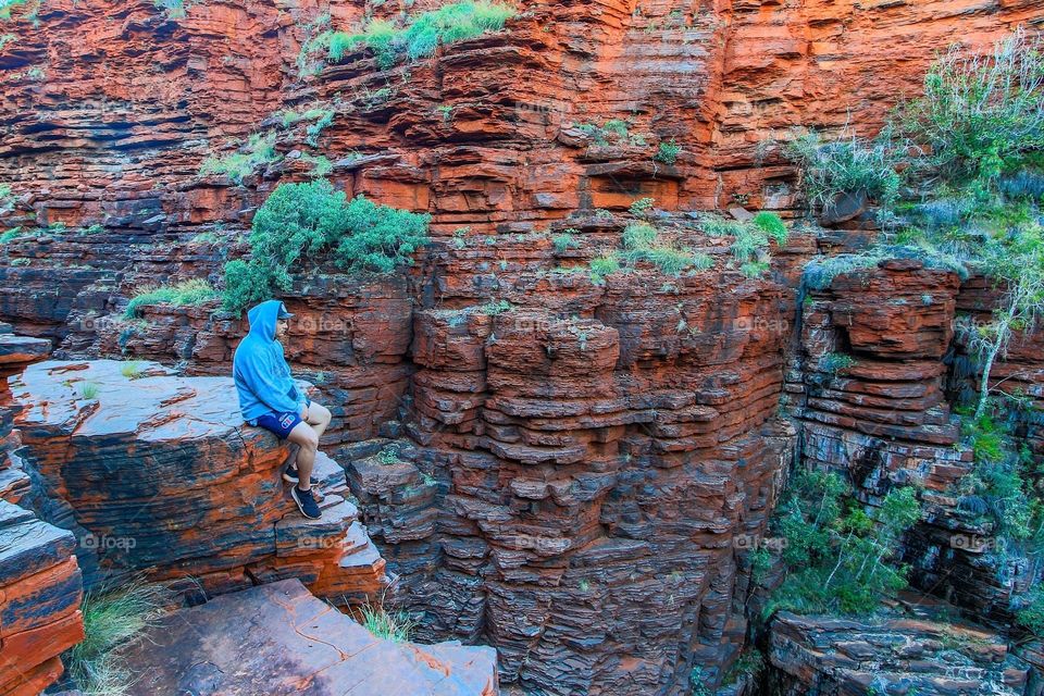 Man sitting on ledge overlooking rocky gorge