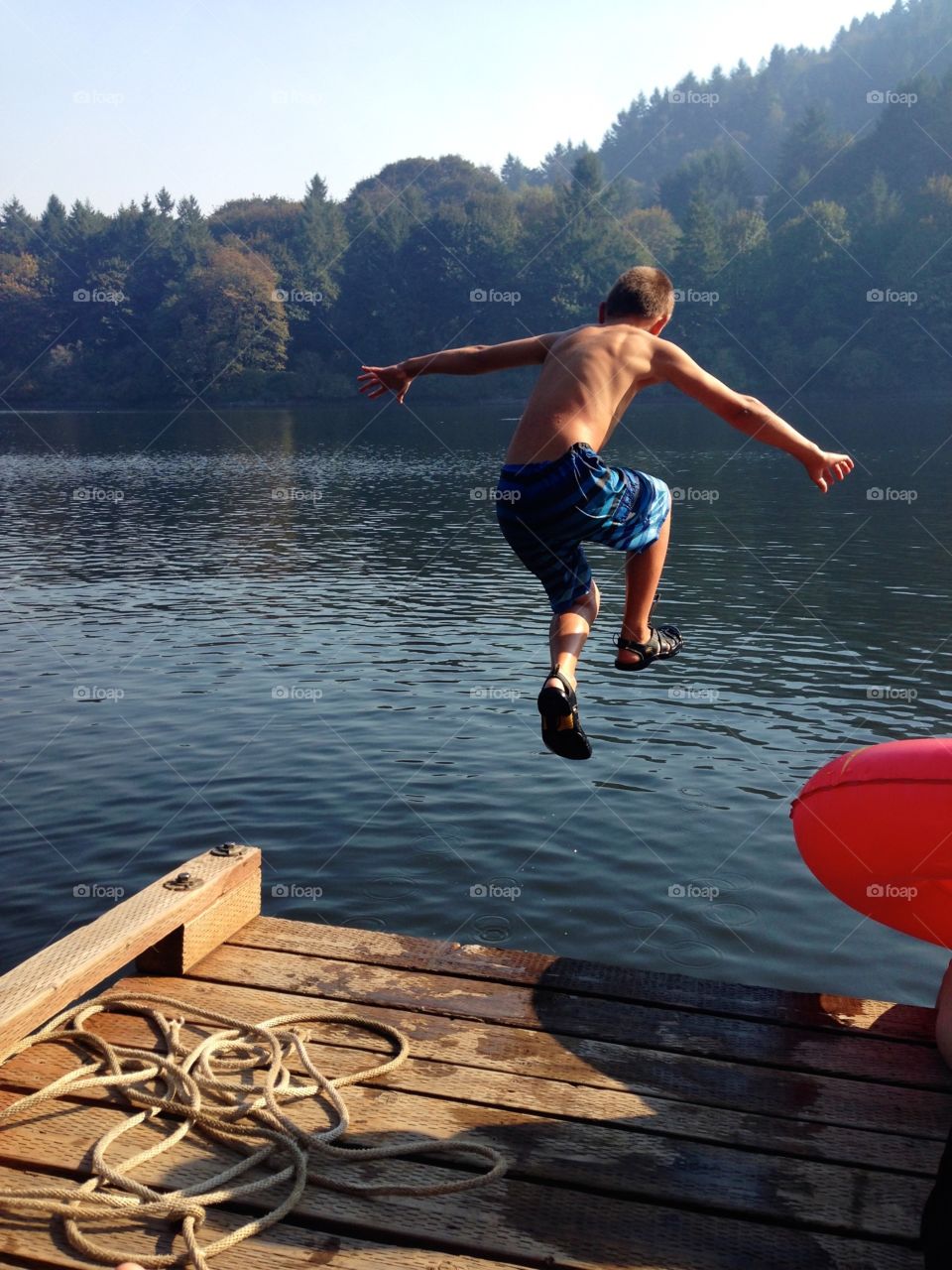 Jump In A Lake. Boy jumping off Dock into a lake