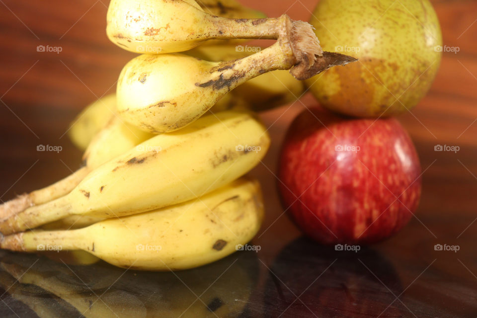 one apple one pear and group banana with wood background.