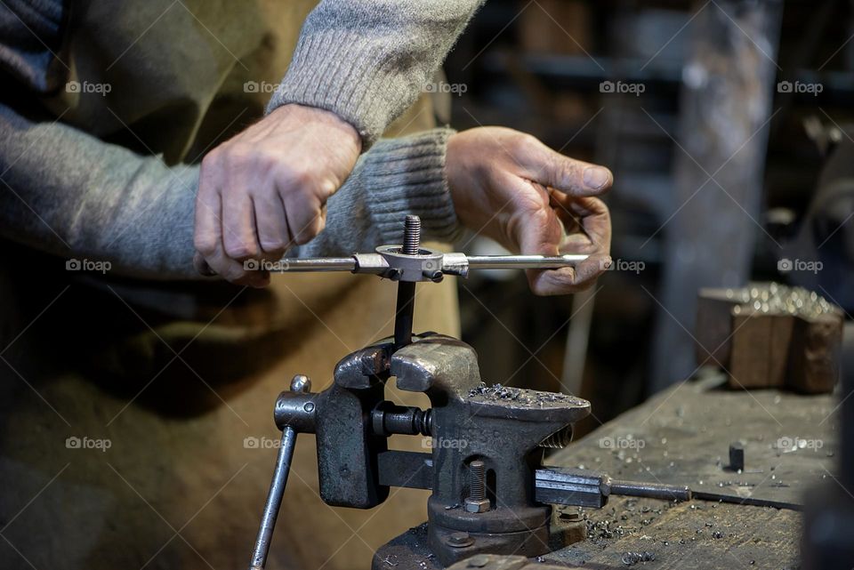 Blacksmith working at with metal at forge