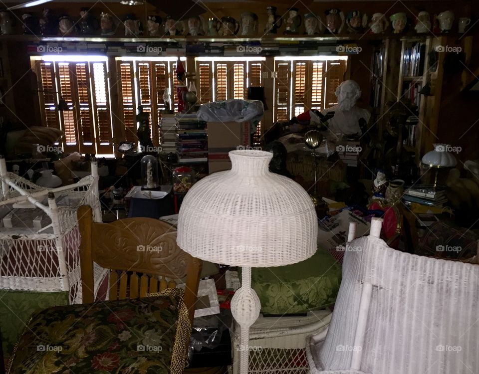A white vintage lamp in the front of antiques stacked in a room