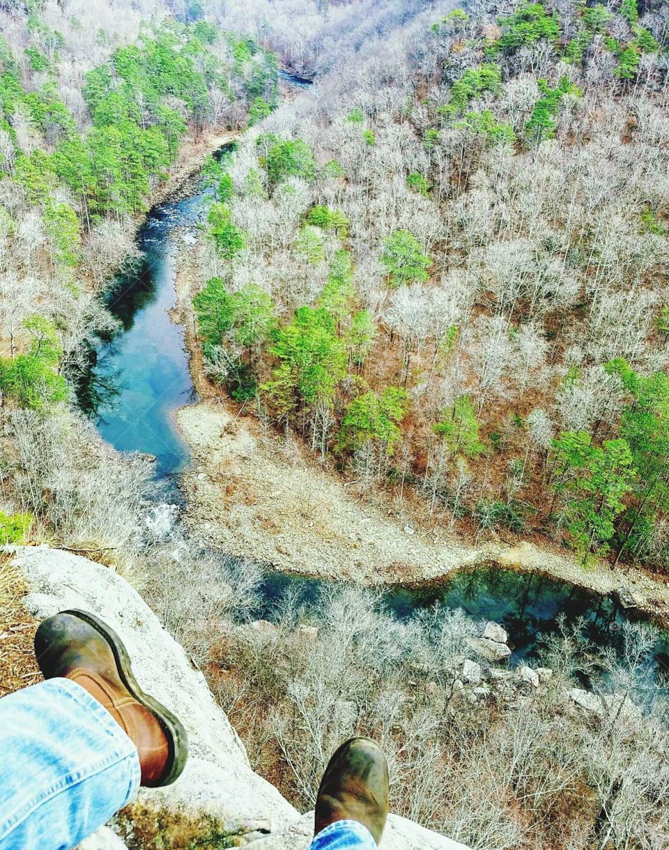 sitting on the edge of a cliff with blue jeans and work boots