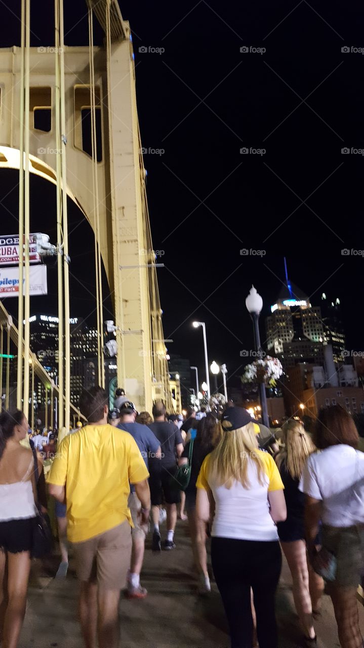 Crossing a bridge with other commuters to get from on part of the city to another at night.