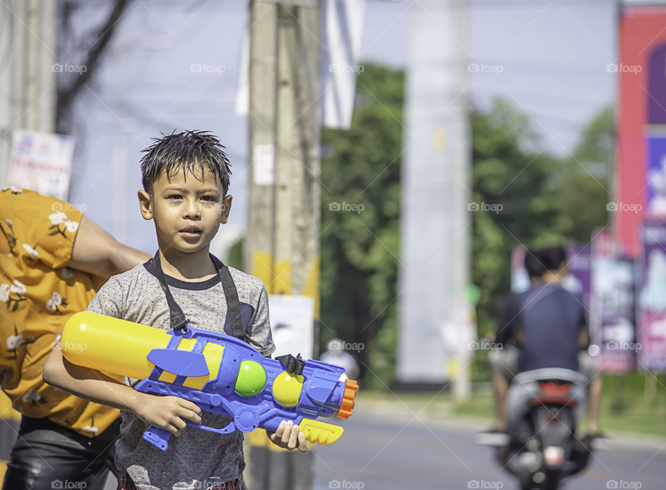 Asian boy holding a water gun play Songkran festival or Thai new year in Thailand.