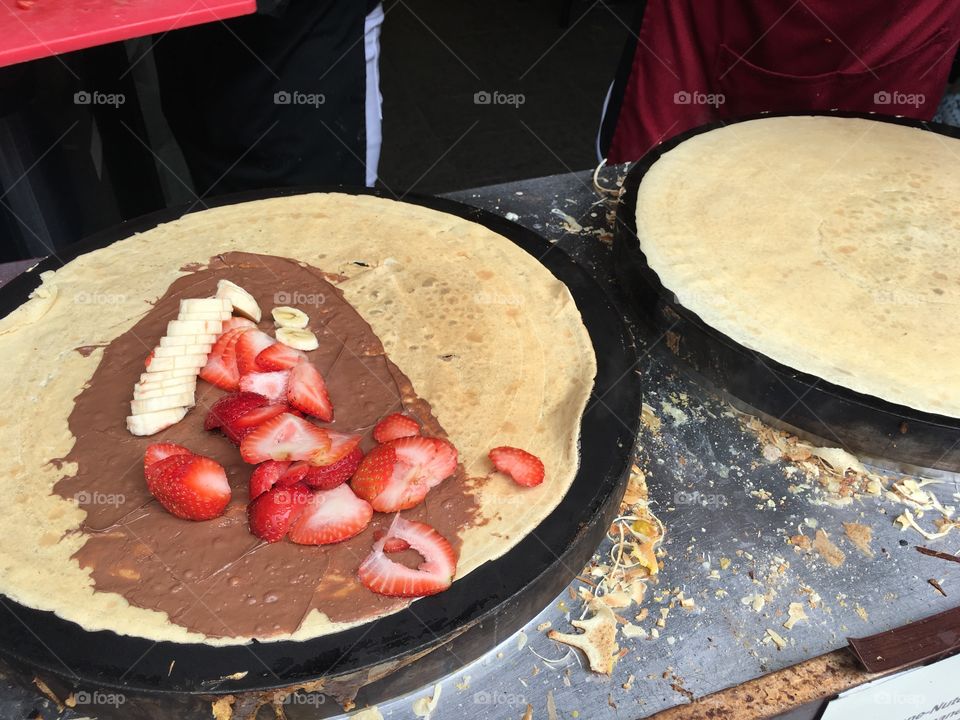 Making crepes with fresh strawberries, chocolate and banana 