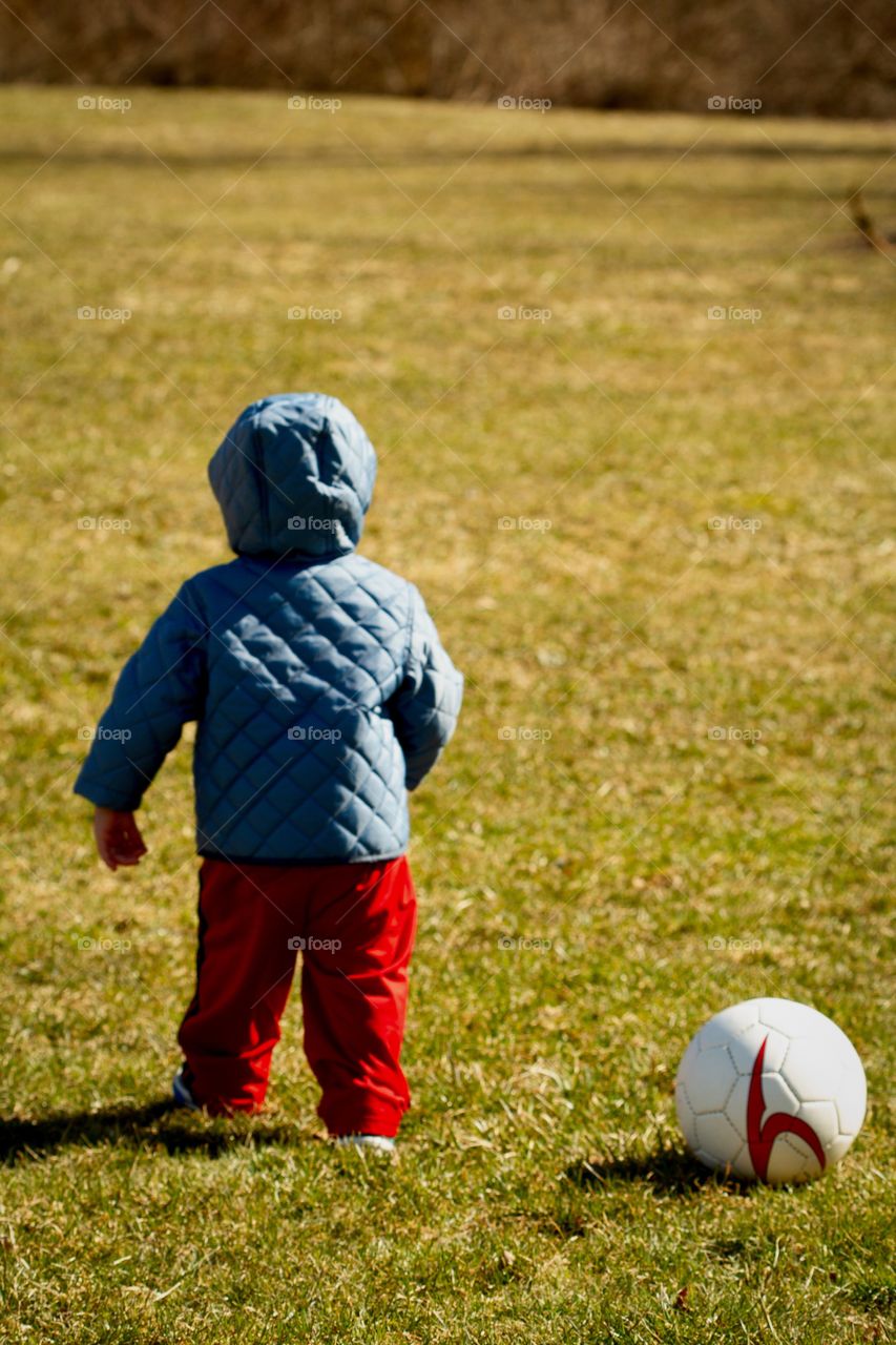 Toddler walks past soccer ball