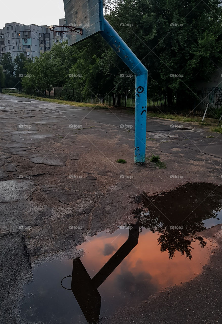 Abstract image of basketball post reflected in a puddle after rain.