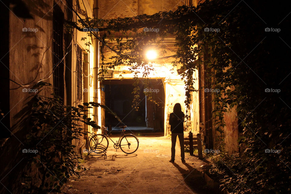 silhouette of a lonely guy with a bicycle in the dark courtyard