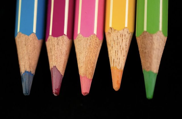 Colored pencils in a row with a black background