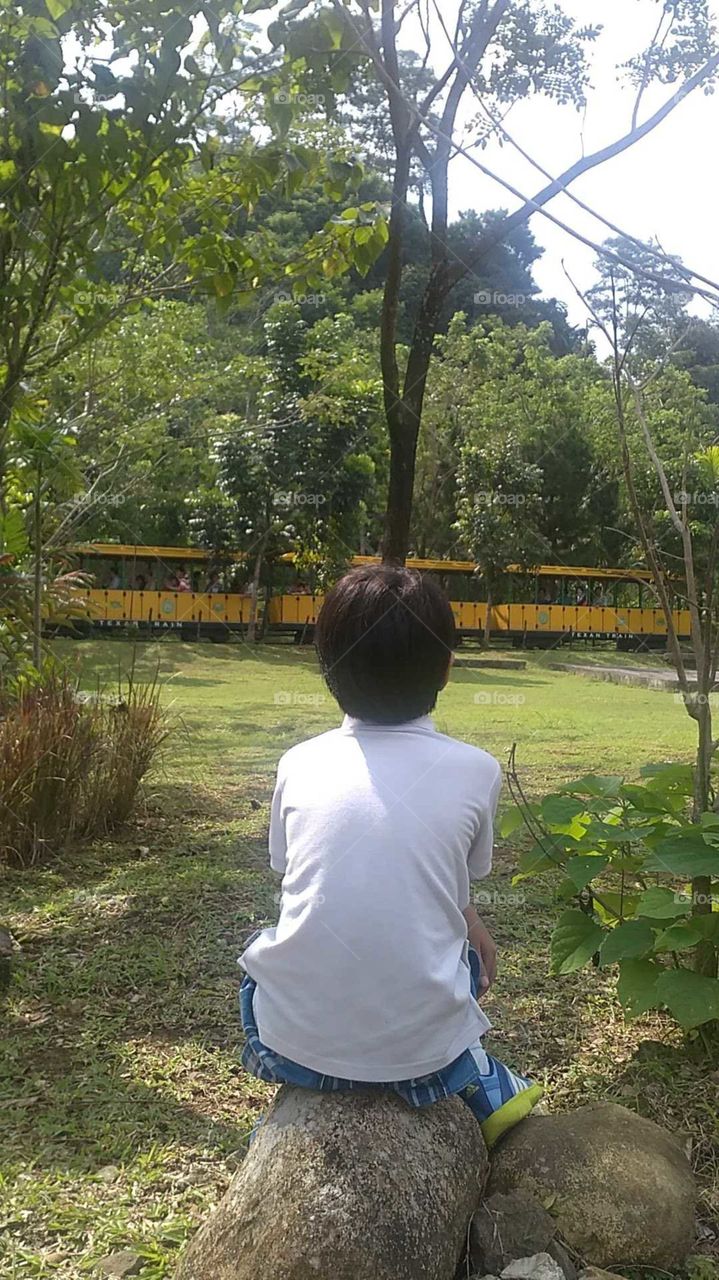 A boy sees a passing by train