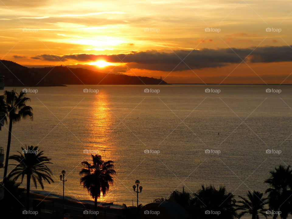 Scenic view of beach with dramatic sky during sunset