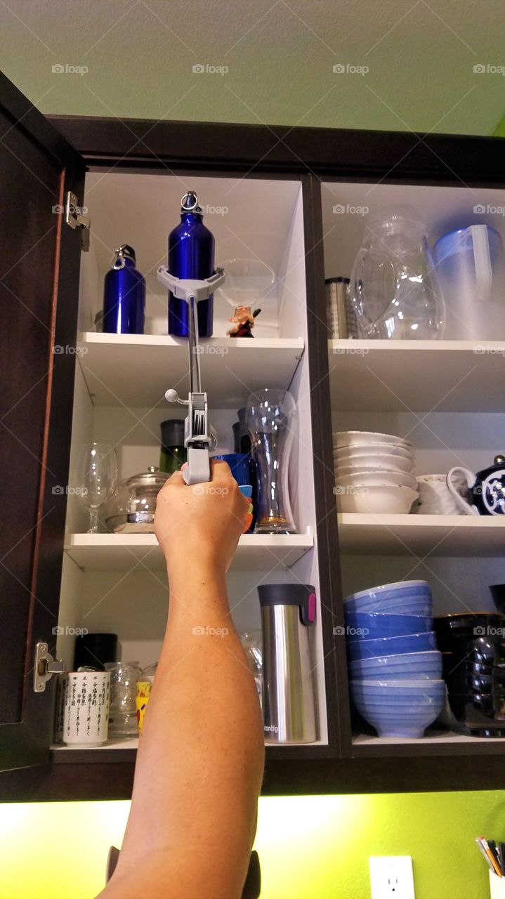 Picking up bottle from the top of the shelf