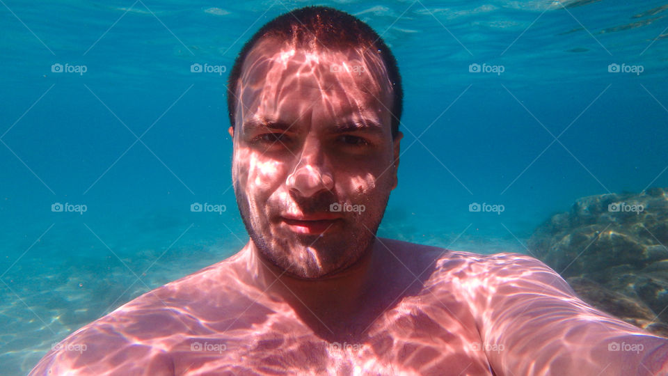 Portrait of a man underwater with sun rays