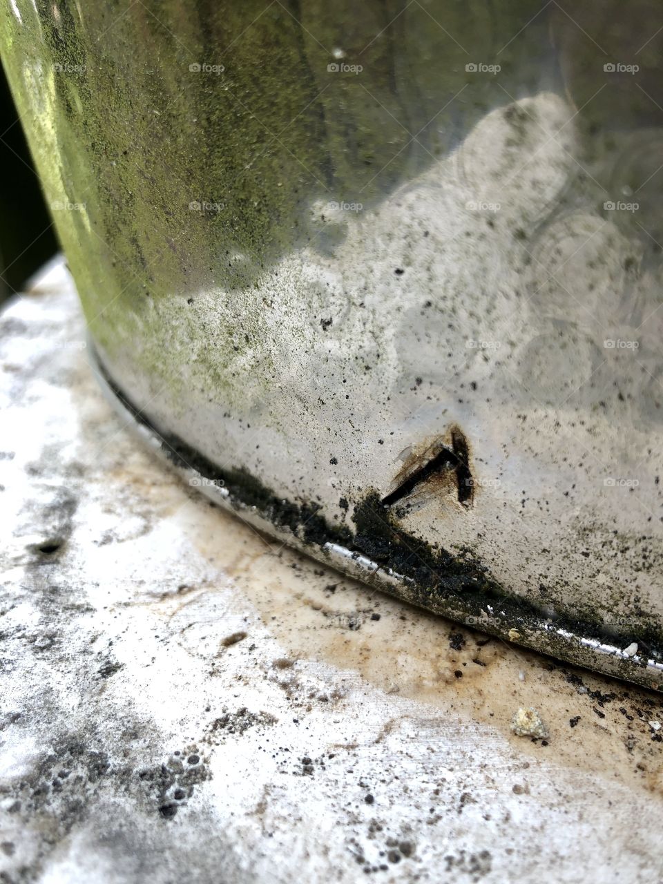 Hammered metal tub with drainage holes on granite surface 