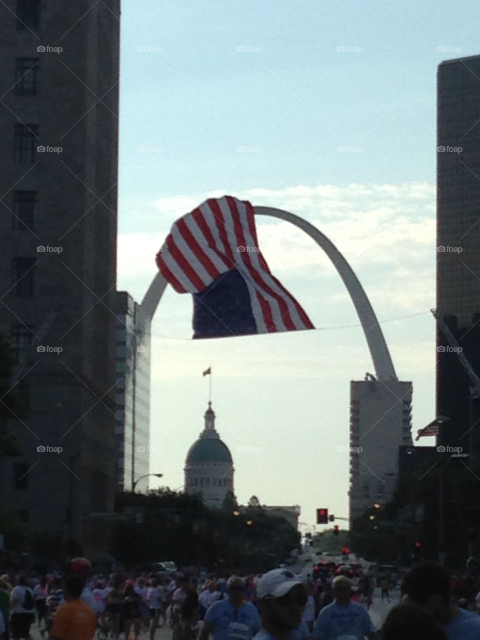 Flag flying with the arch and old courthouse 