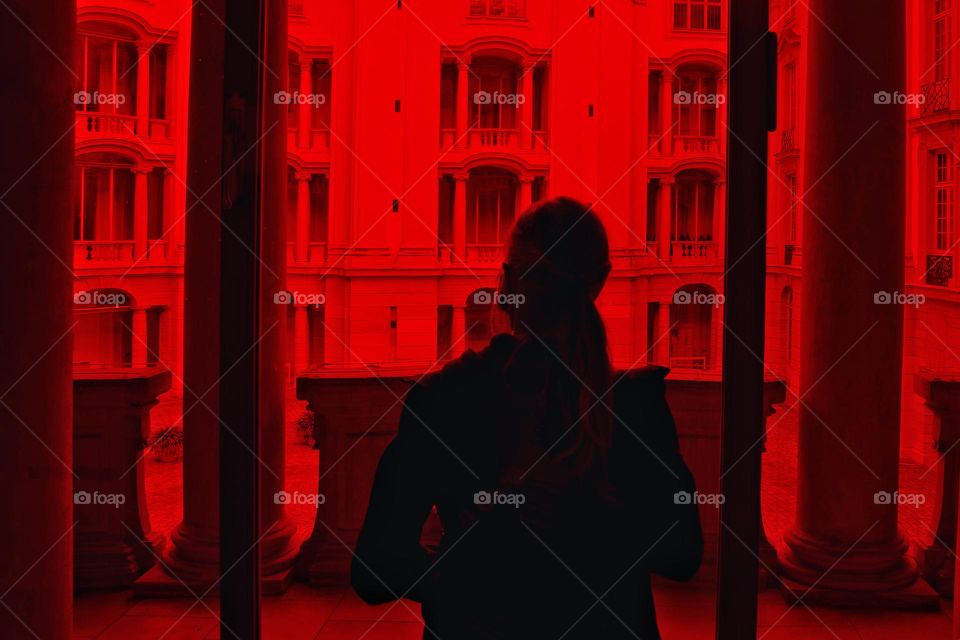 Rear view of a woman looking to a building in red light