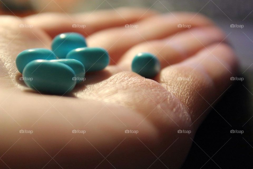 Handful of candy. Blue tic tacs in a hand