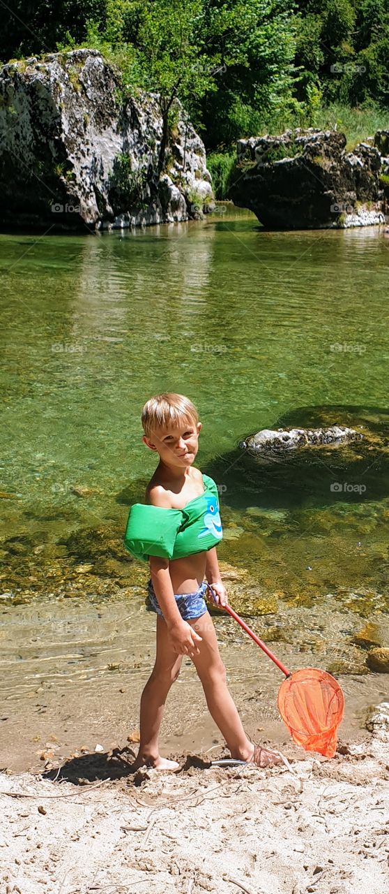 a boy with a net at mountain river shore
