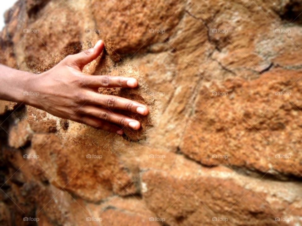 a hand touching a wall made with stones