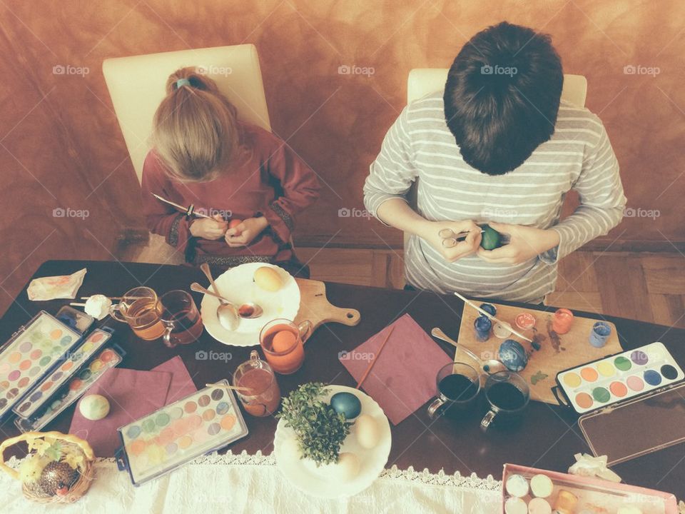 Brother and sister painting Easter eggs at home