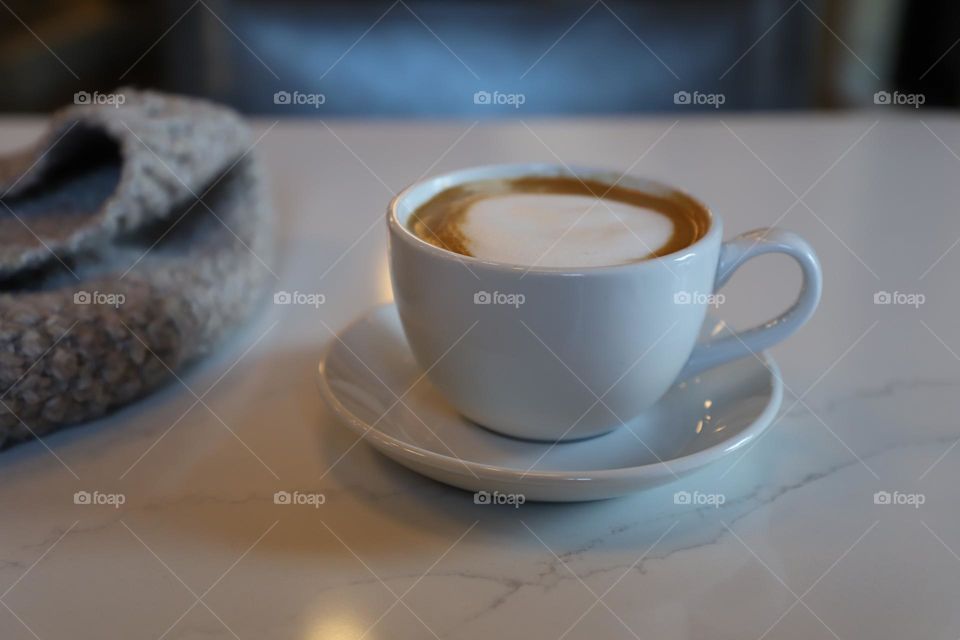 Cappuccino and hat on tabletop 