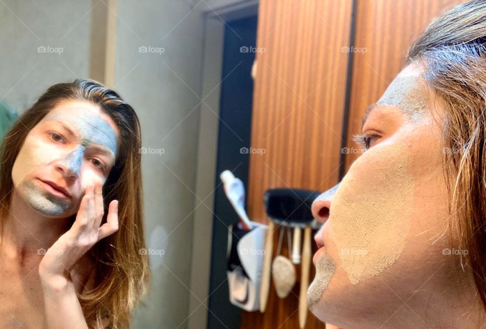girl in the bathroom applying the mask in front of the mirror.  cosmetics