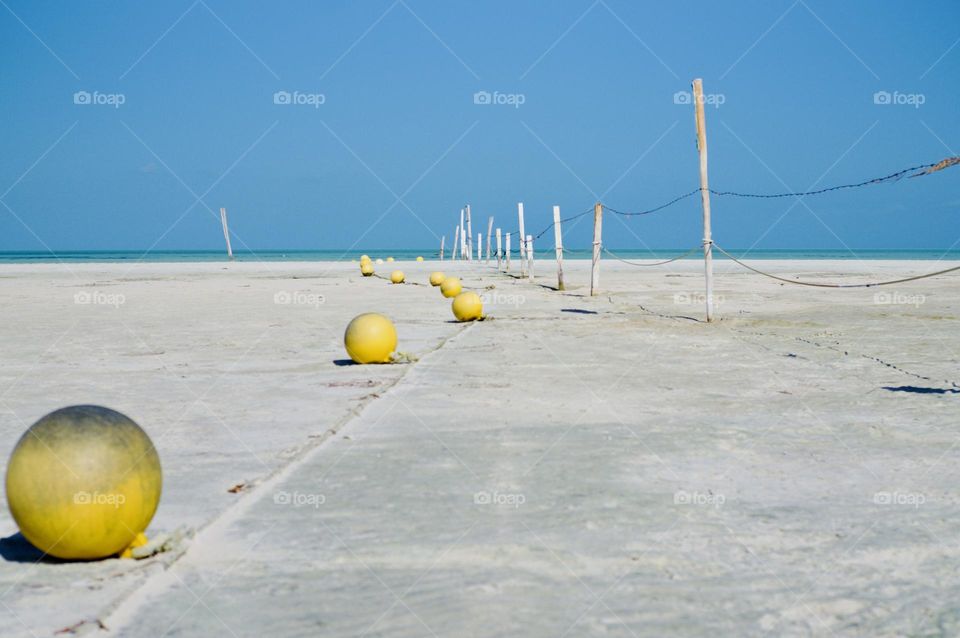 Fence and buoys in the sand.