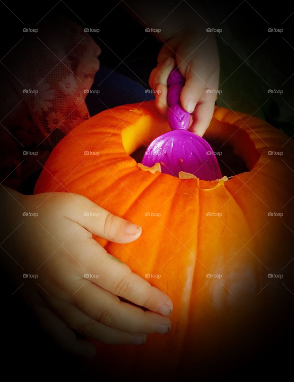 Child scooping a Halloween pumpkin