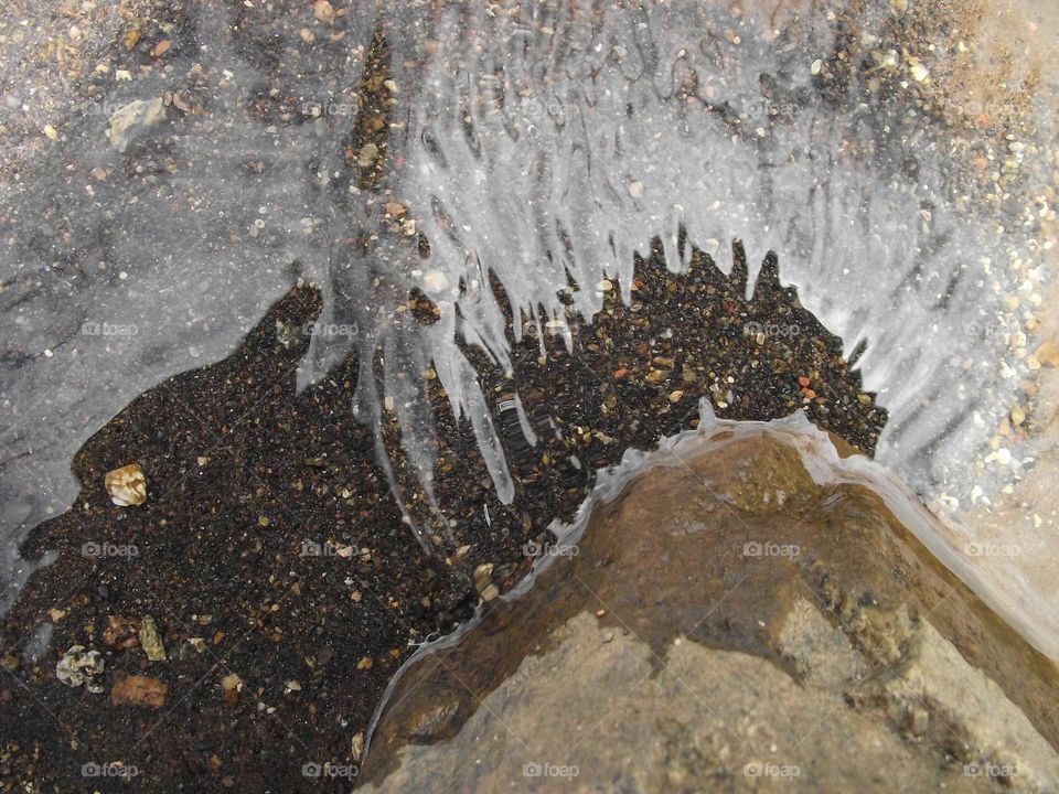 white sky reflecting on the water make it appear white but when the water bounces on the rock it because transparent