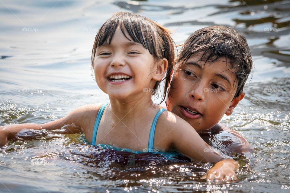 Sister and brother are happily swimming together