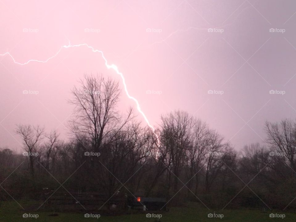 Flash of lightning along purple tinted sky