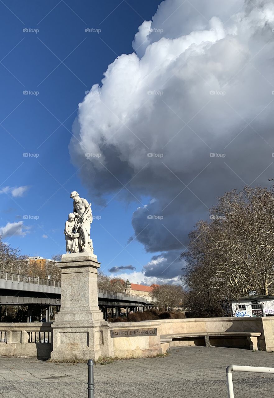 Ominous clouds overlooking a statue on Hallesche-Tor-Brücke in Berlin.