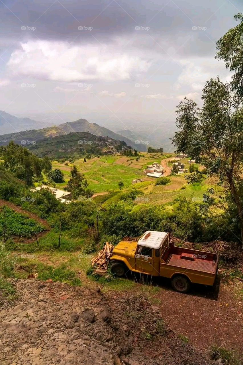 The image embodies a natural natural plate of the mountains of nature, where green agricultural stands are graded on the slopes as if they were lines of a poem, which fog harmoniously wrapped, and clouds hugged them in the mountain knife and the whis