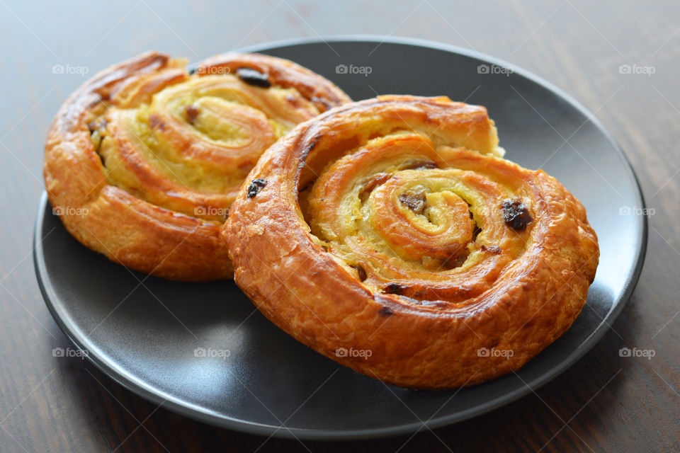 Danish raisin swirls on a black plate.