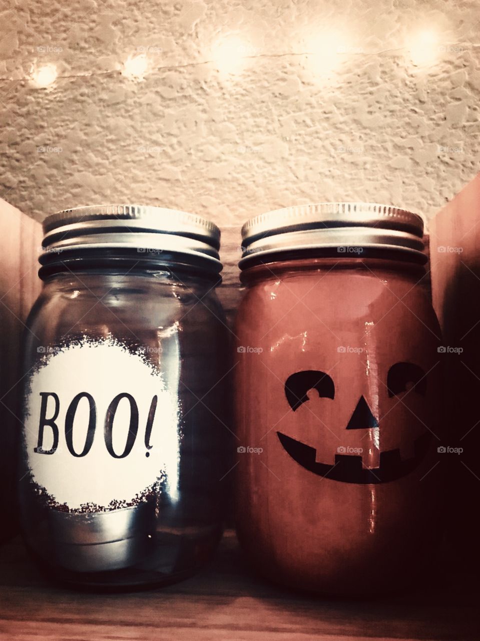 Halloween themed glass mason jars with a pumpkin face and the word boo written on them 