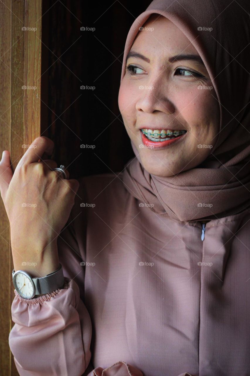 Portrait of a smiling young Muslim woman wearing a pink hijab (Chewing Gum color). Modern Hijab. Happy Expression.