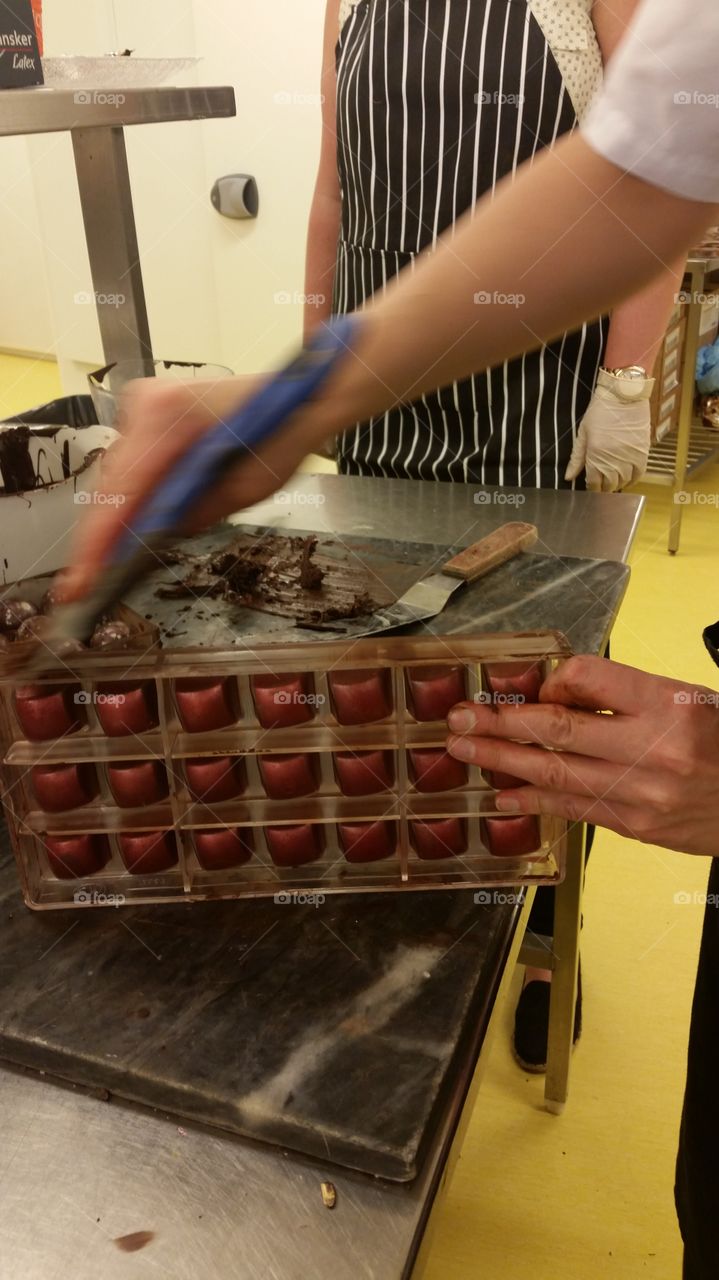 Removing the excess chocolate from a mold with dusted shells, almost ready to be filled.