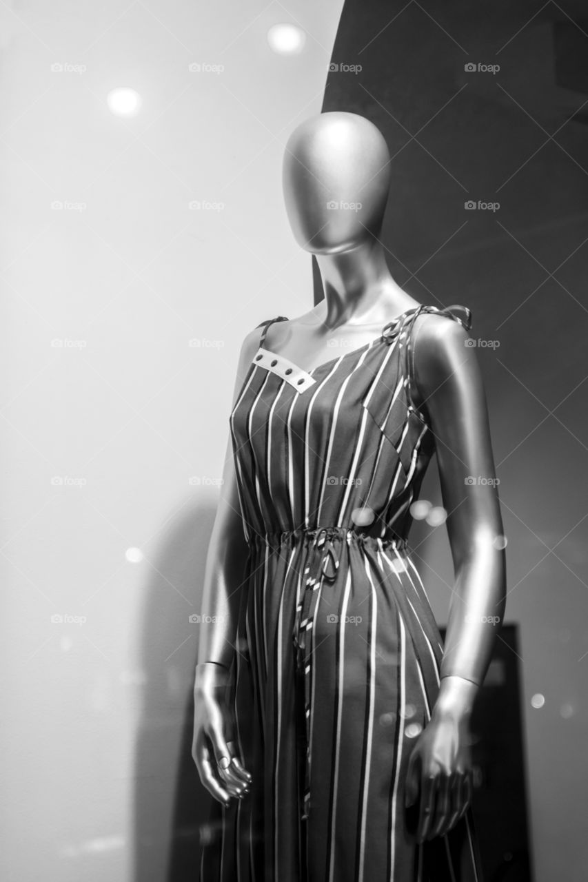 Mannequin standing in store window display of women's casual clothing. Close-up of a plastic mannequin. Black and white