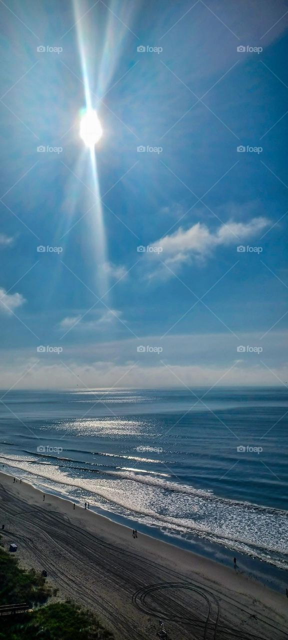 North Carolinas beach front veiw of the ocean from 15th floor of a hotel the sun is shining down with a radiant spotlight effect and minimal clouds