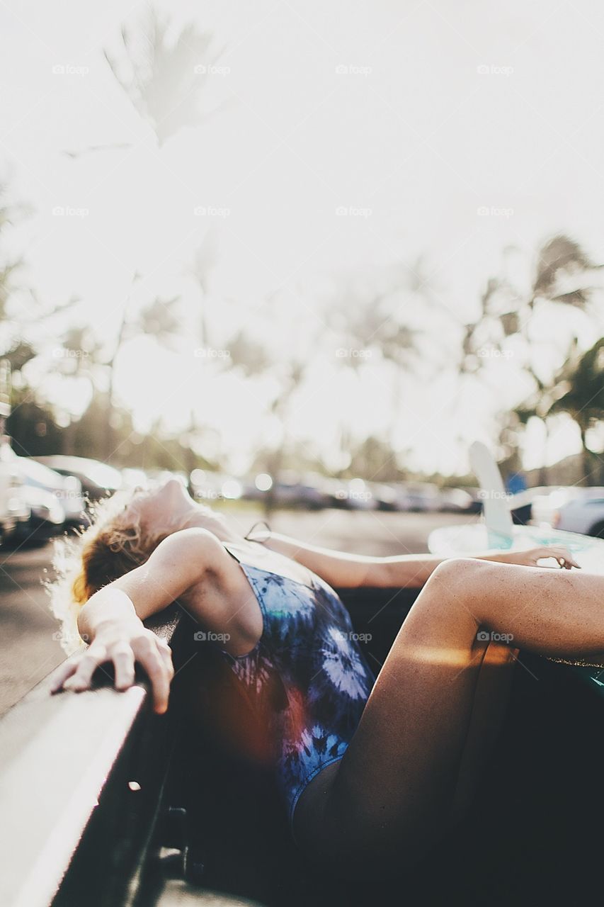 Girl relaxes in the back of a truck during a summer morning.