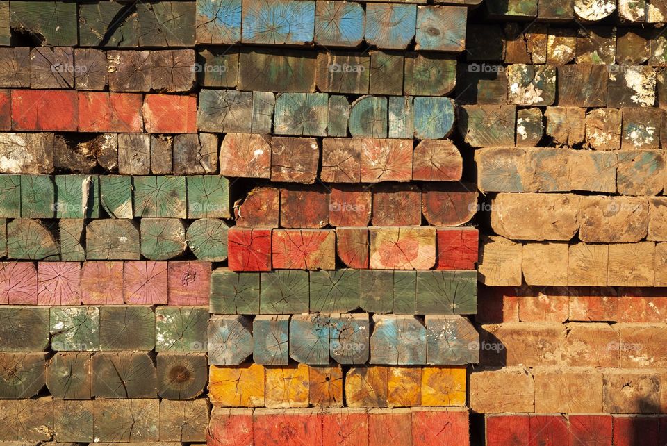 A stock pile of multicolored assorted wooden logs is stored for future use at a timber yard.